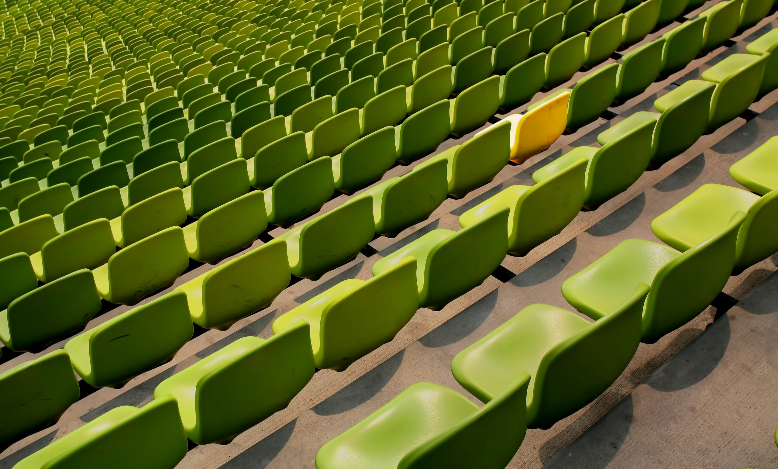 A row full of green chairs with one yellow chair